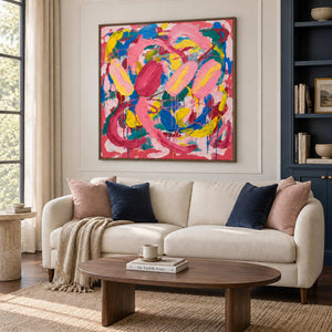 In Full Swing in a brown wood frame above a cream sofa with navy and blush cushions in a bright living room.