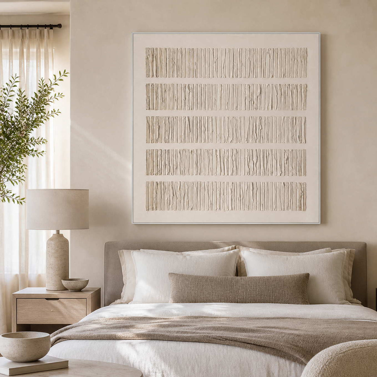 White framed cream abstract artwork above a softly layered neutral bed.