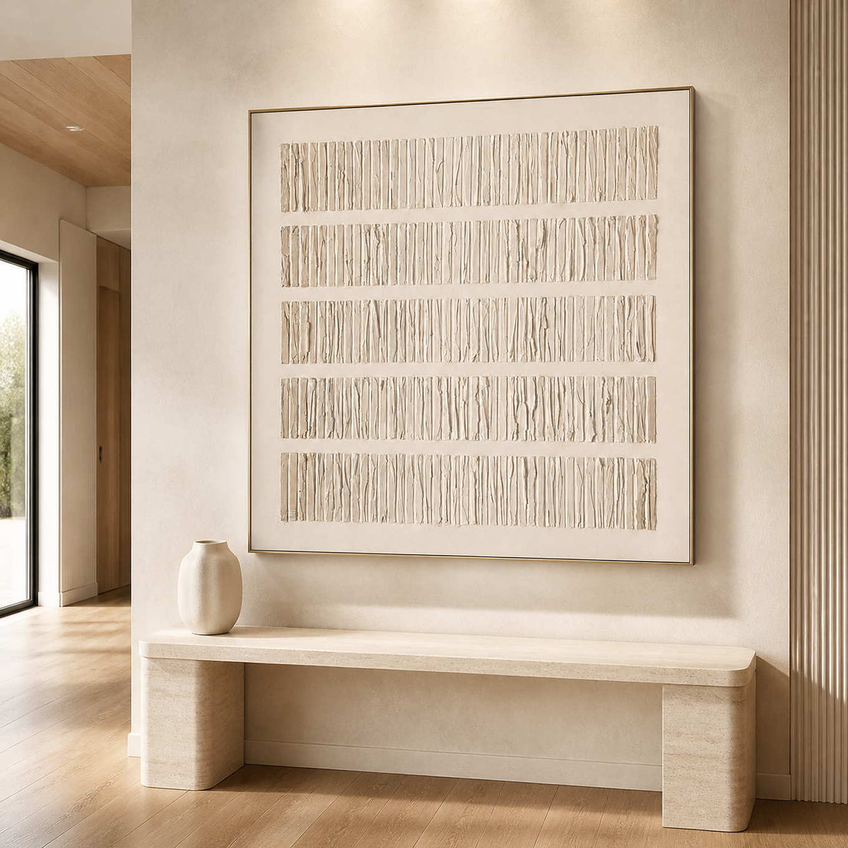 Gold framed cream textured artwork above a pale stone bench in a hallway.