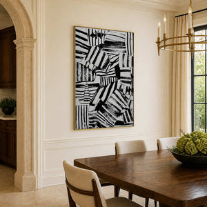 Gold-framed striped abstract wall art displayed beside upholstered chairs in a warm dining room.