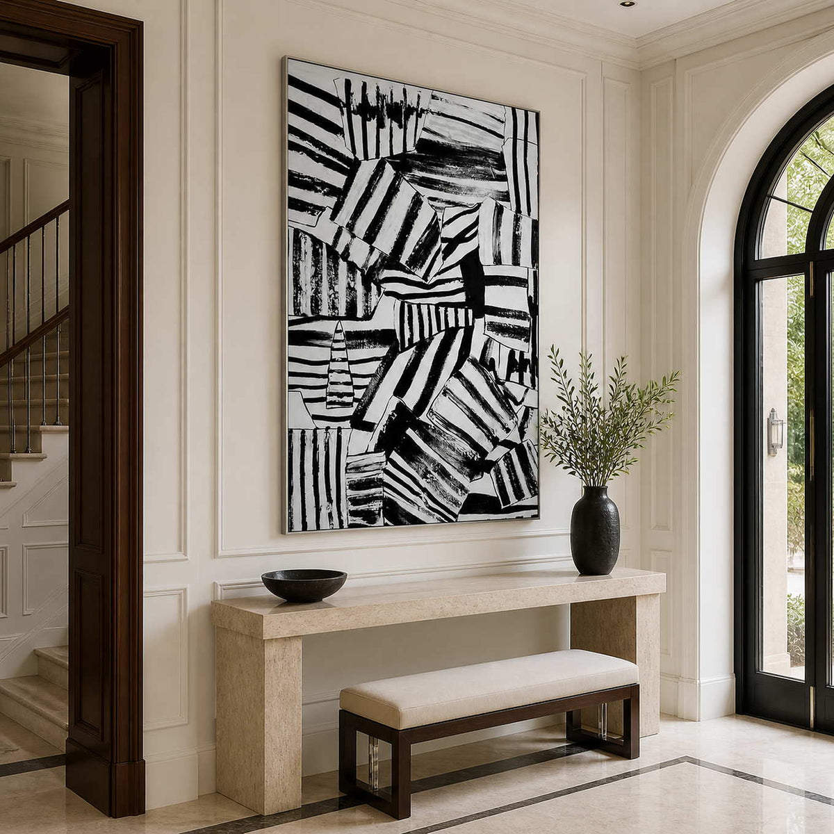 Silver-framed abstract wall art above a stone console beside an arched entryway window.