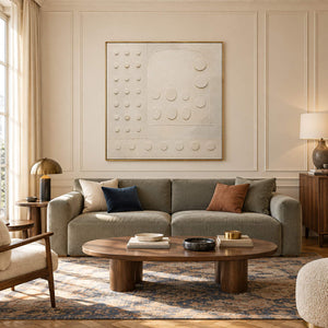 Warm white textured wall art with raised circles and quiet geometry, displayed in a living room in a gold frame.