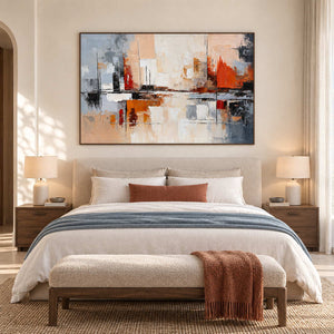Wide cream and orange artwork above a bed with a blue-gray throw and rust-colored accents.