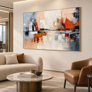 Orange-accented abstract artwork in a sitting room with a cream sofa and brown leather chair.