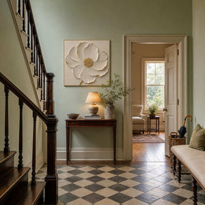 Square textured floral wall art styled beside a staircase in a bright entryway.