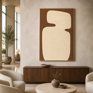 Gold framed brown and cream artwork above a cabinet in a hotel lounge.
