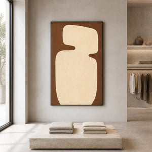 Black framed cream abstract artwork above folded textiles in a neutral clothing showroom.