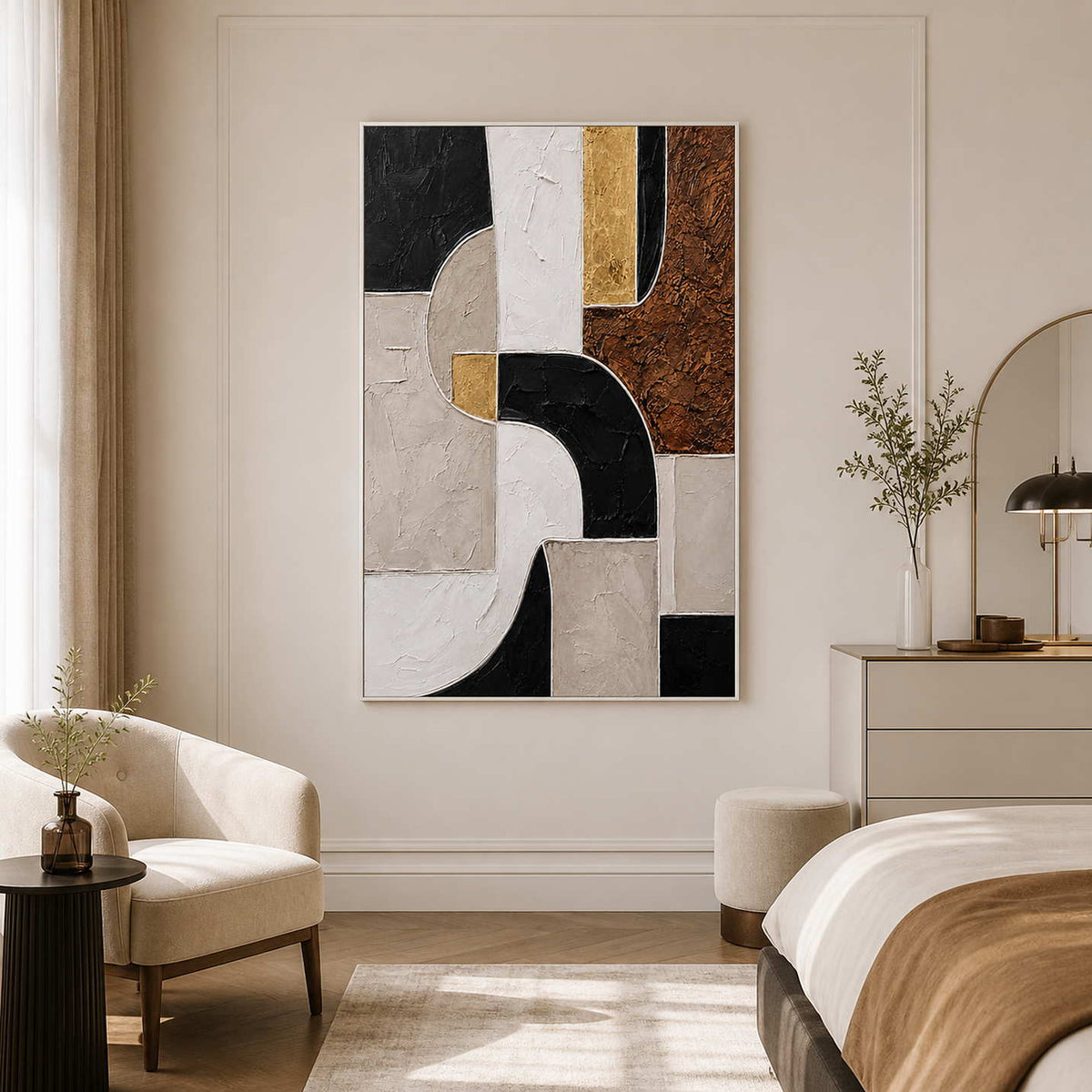 White framed geometric artwork beside a bed and cream chair in a bright bedroom.