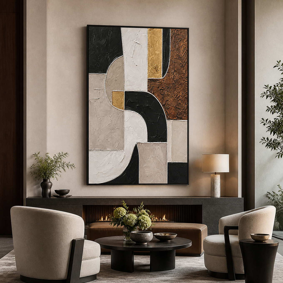Black framed geometric artwork above a hotel fireplace with cream chairs and a round table.