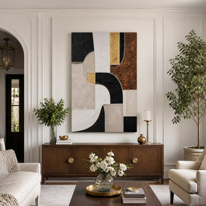 Frameless geometric artwork above a wooden sideboard between cream living room seats.