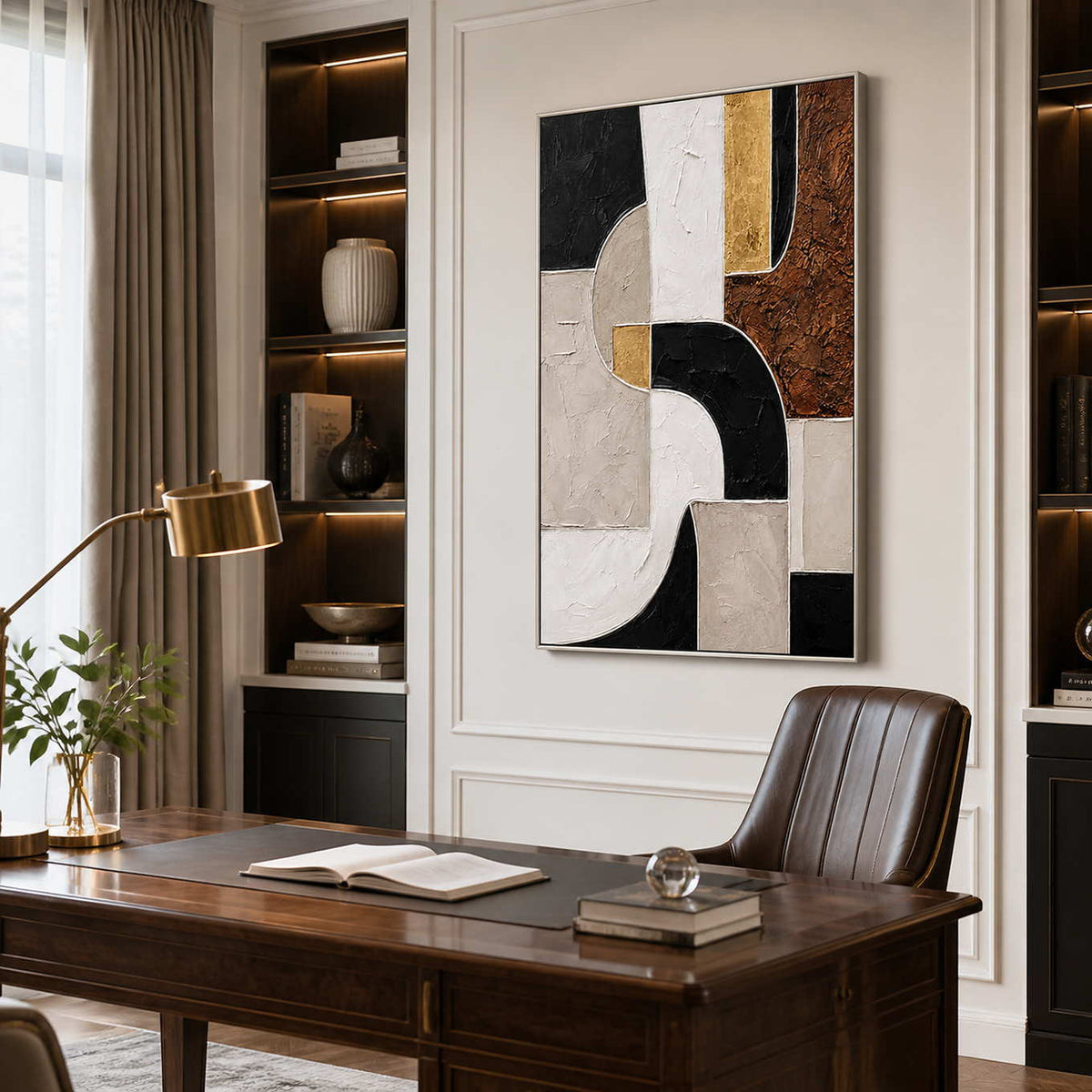 Silver framed geometric artwork above a wooden desk with a brown leather chair.