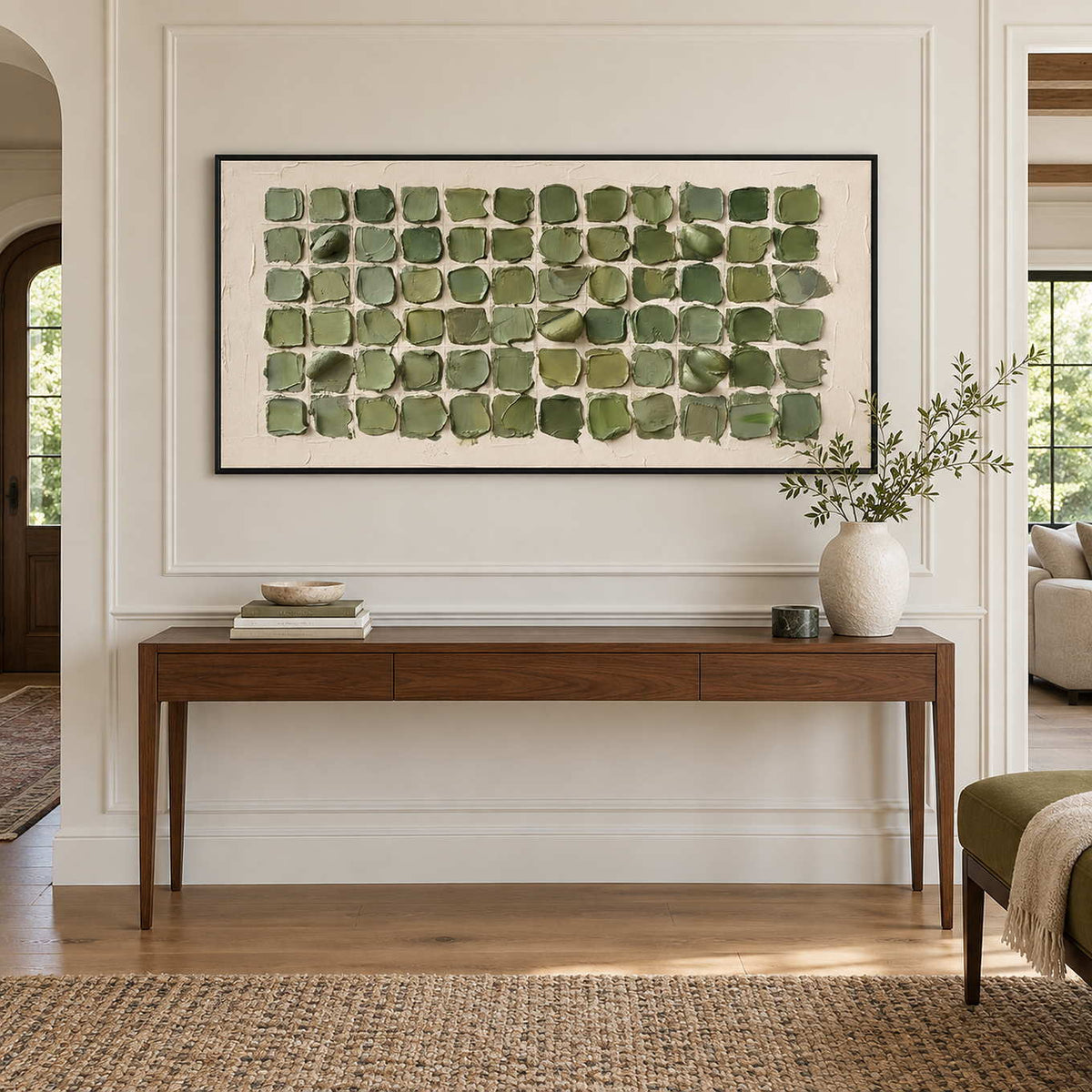 Keeping a Little Spring in a black frame above a slim wood hallway console with books and a leafy vase.