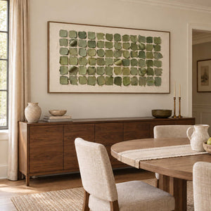 Keeping a Little Spring in a wood frame above a dark sideboard beside a round wood dining table and cream chairs.