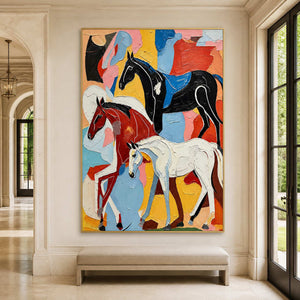 Gold framed equestrian painting with black, red-brown, and white horses above a hallway bench.