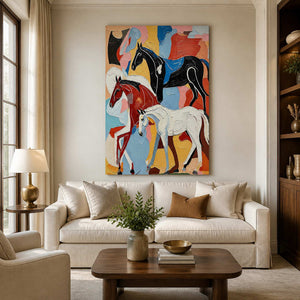 Frameless colorful equestrian artwork showing three horses above a cream living room sofa.