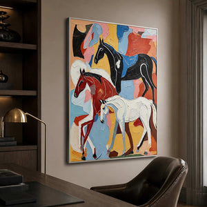 Silver framed artwork showing three colorful horses beside a home office bookshelf.