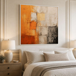 White framed warm abstract wall art above a neutral upholstered bed.
