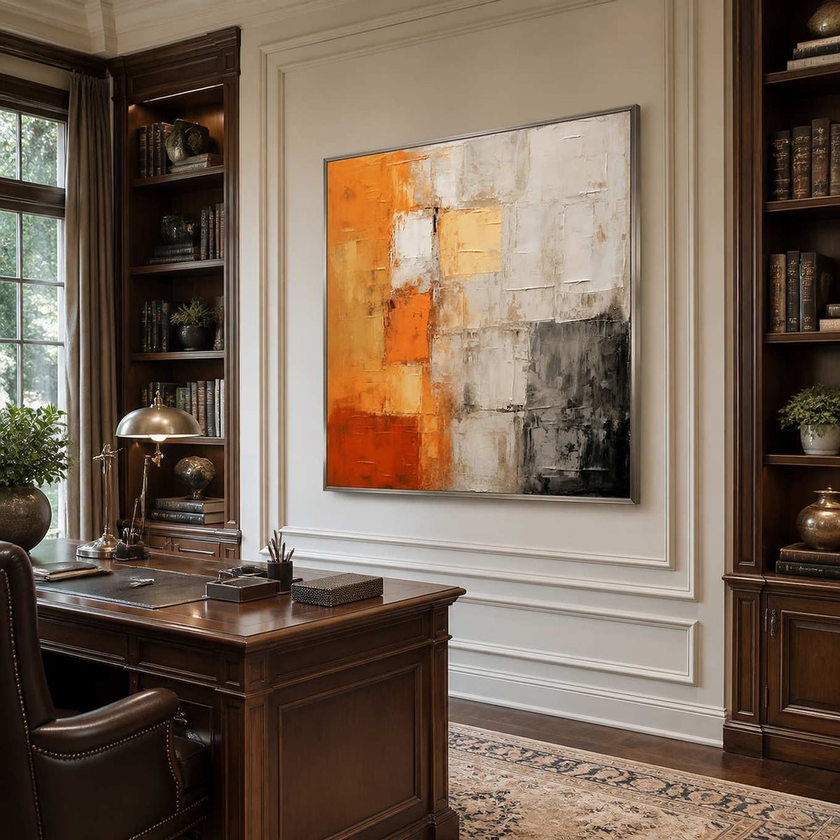 Silver framed orange and gray abstract painting between dark wooden bookshelves.