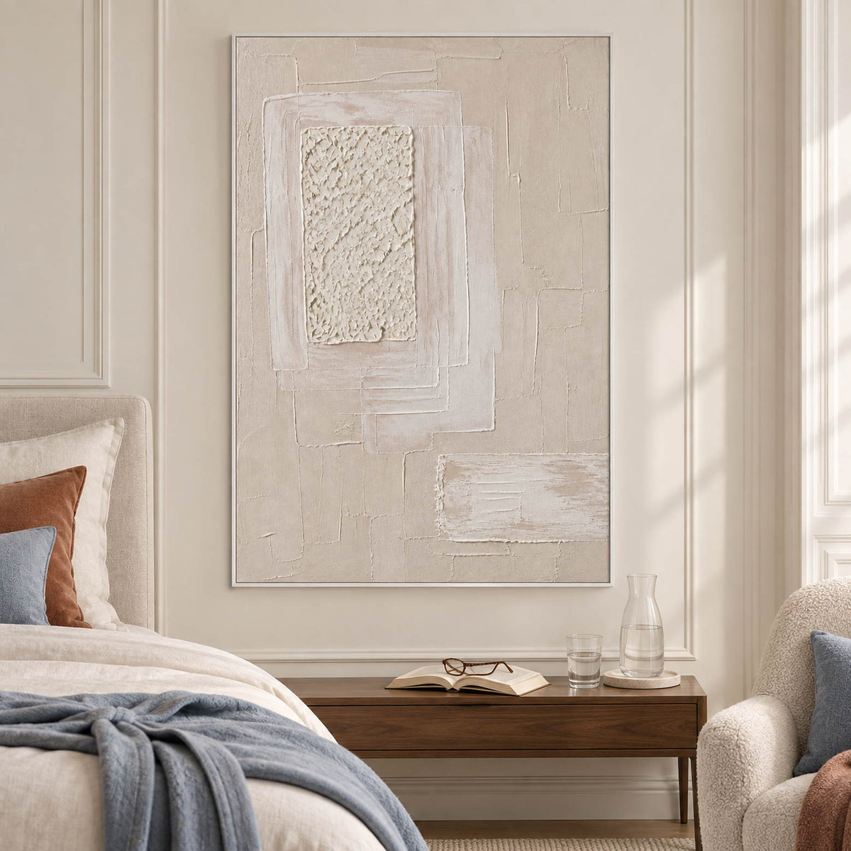 Ivory and blush relief painting with layered rectangles and a rough central panel in a white frame in a bedroom.