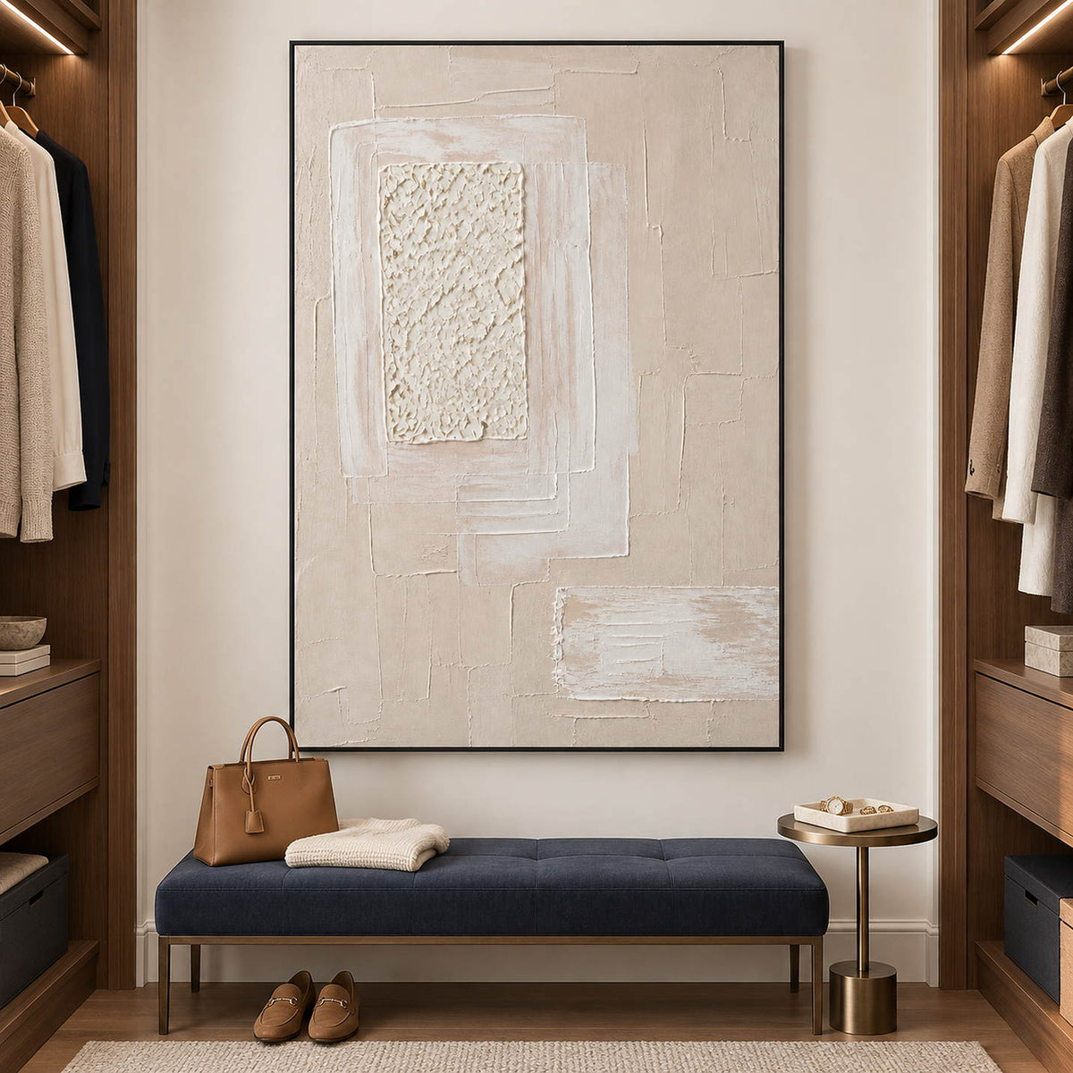 Ivory and blush relief painting with layered rectangles and a rough central panel in a black frame in a dressing room seating area.