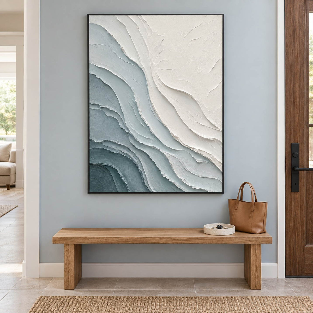 Layered blue-gray and chalk-white coastal relief painting in a black frame in an entryway.