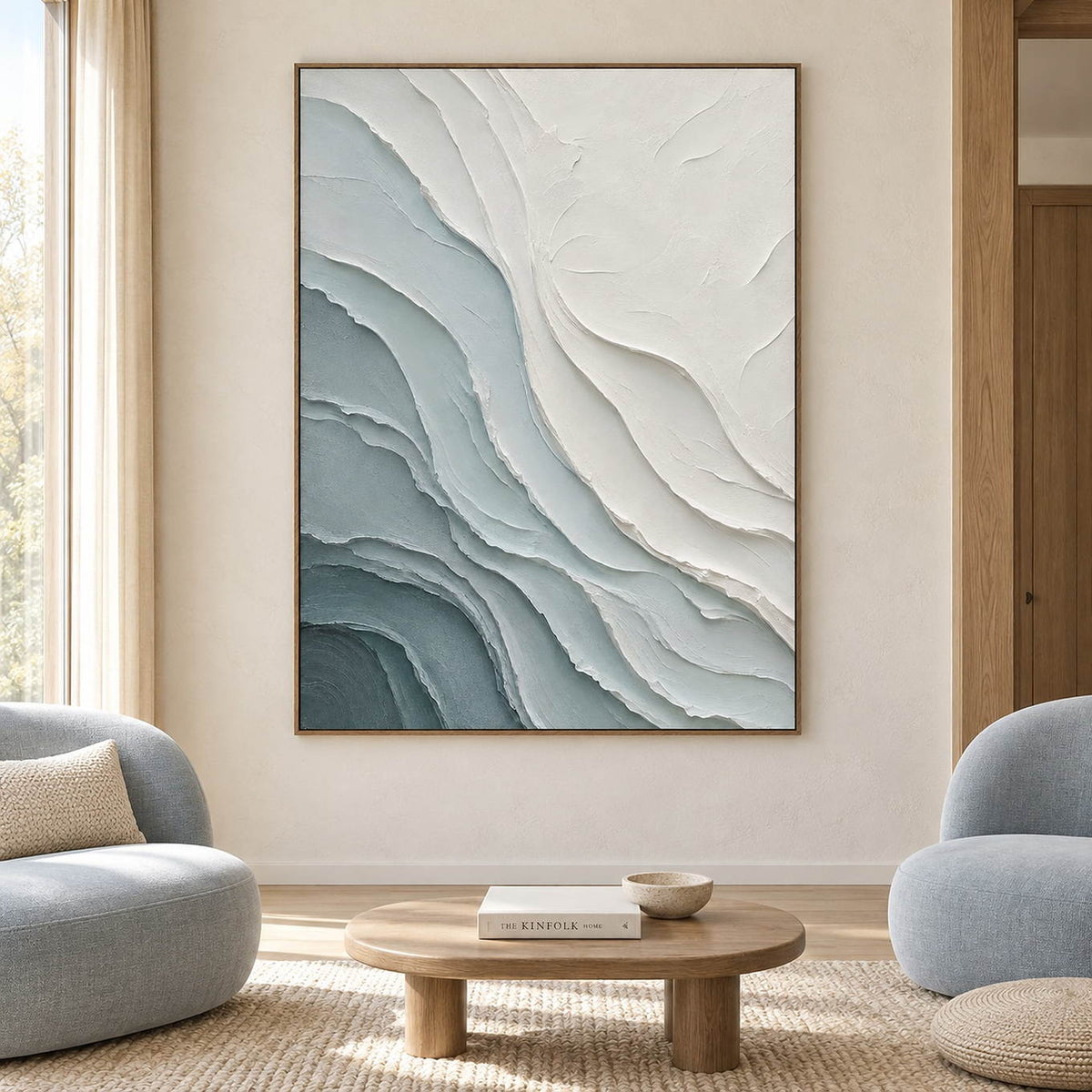 Layered blue-gray and chalk-white coastal relief painting in a brown wood frame in a living room.