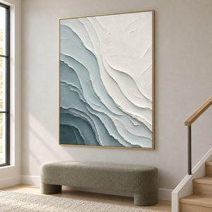 Layered blue-gray and chalk-white coastal relief painting in a gold frame on a stair landing.