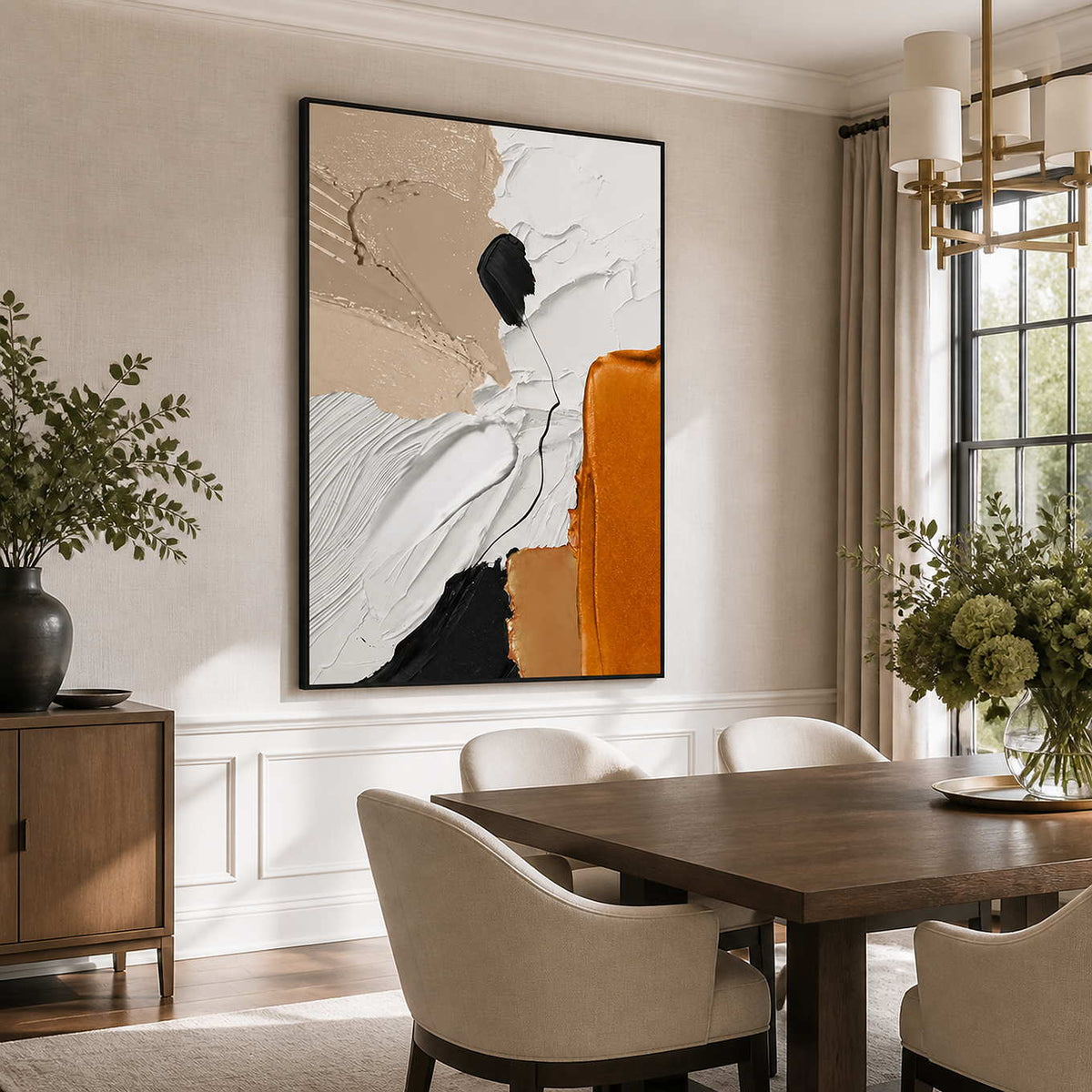 Black framed orange and white abstract painting beside a wooden dining table and cream chairs.