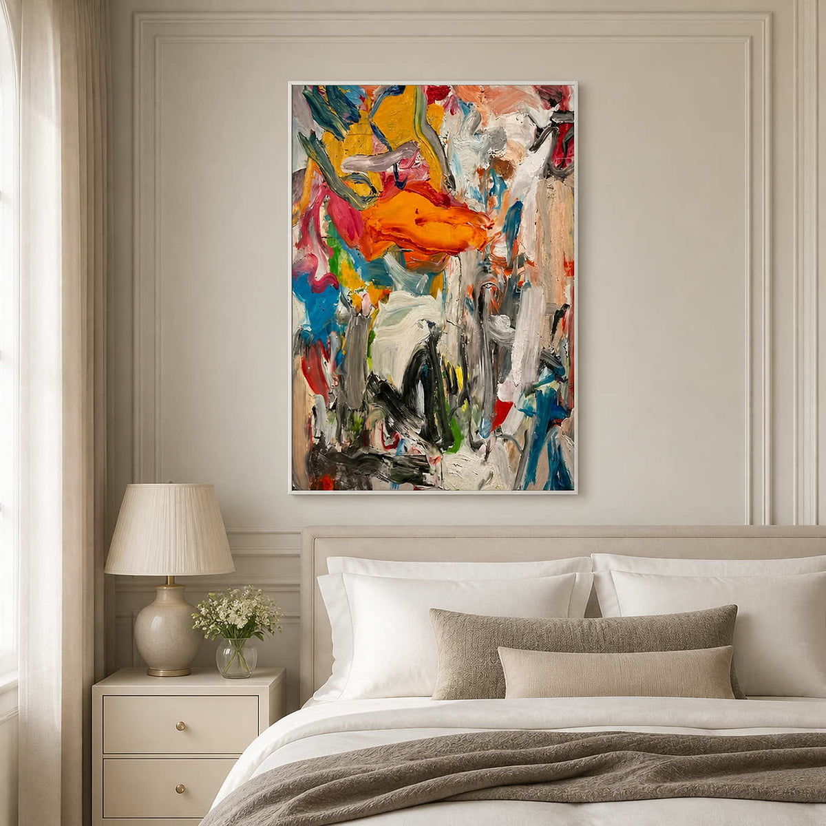 White framed colorful abstract artwork above neutral bed linens in a bright bedroom.