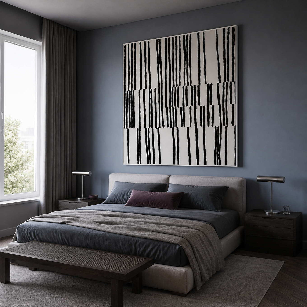 White framed black and white artwork above a bed against muted blue walls.