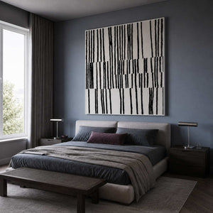 White framed black and white artwork above a bed against muted blue walls.