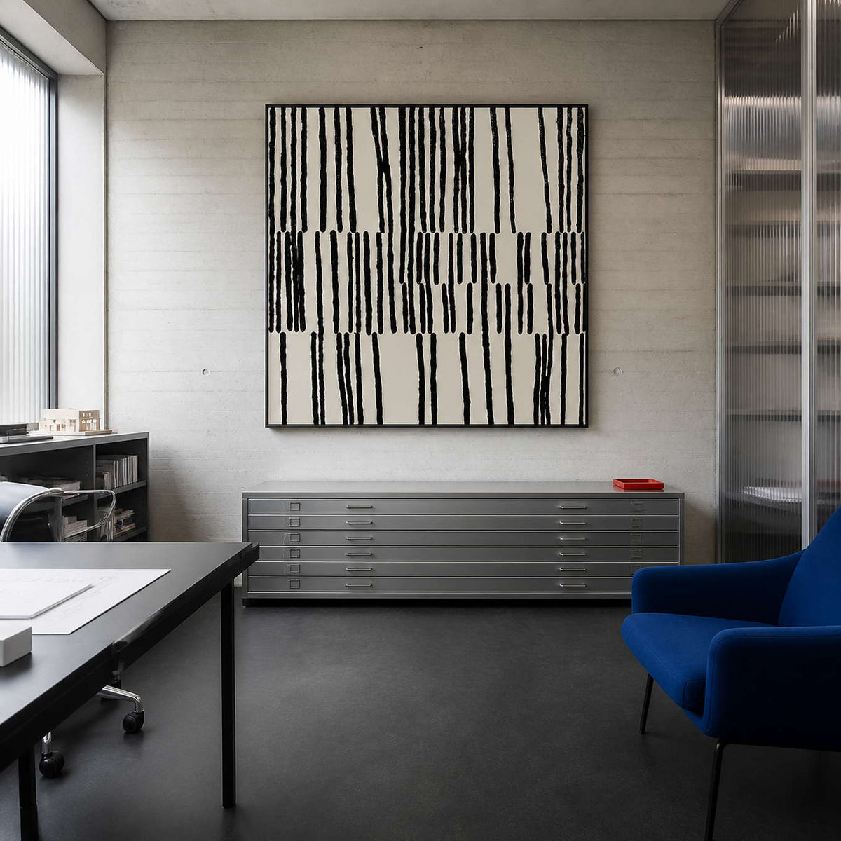 Black framed patterned artwork above metal drawing cabinets in a creative studio.