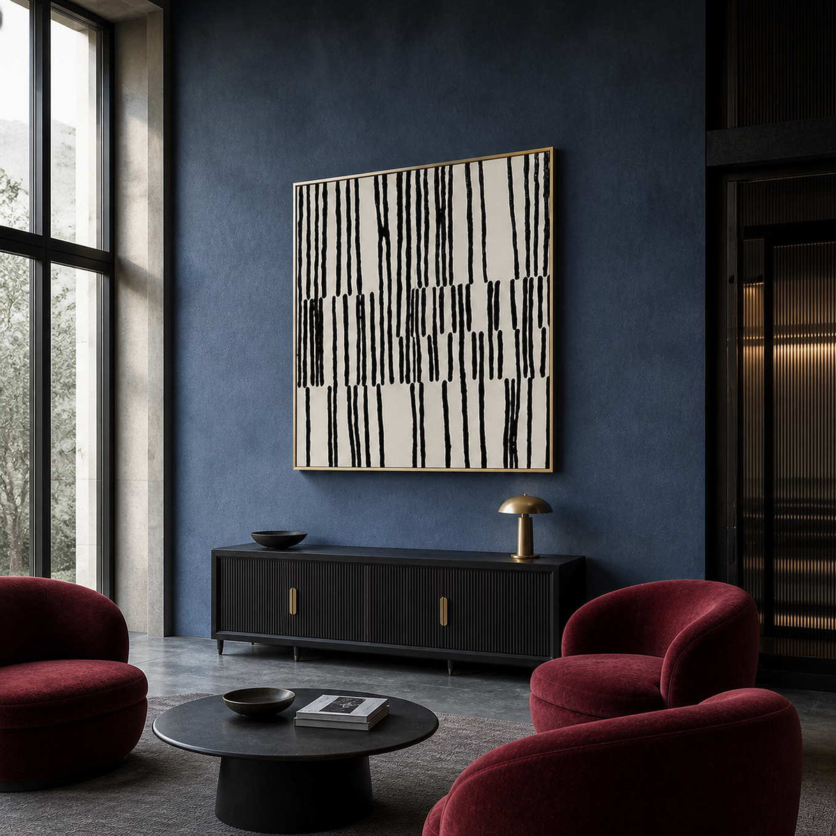 Gold framed black and white artwork beside burgundy chairs in a blue hotel lobby.