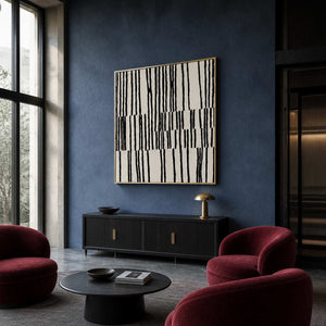 Gold framed black and white artwork beside burgundy chairs in a blue hotel lobby.