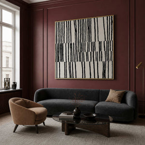 Gold framed black and white artwork above a charcoal sofa against burgundy walls.