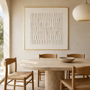 Neutral textured wall art above a travertine dining table.