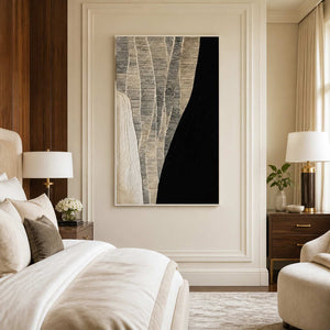 White framed black and cream abstract artwork beside a bed with neutral bedding.
