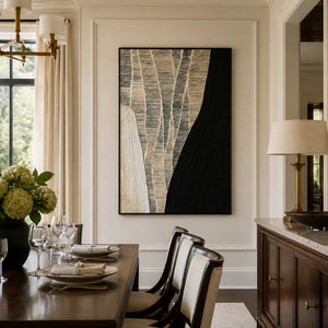 Black framed woven abstract artwork beside a wooden dining table and white chairs.