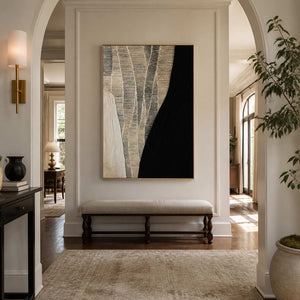 Gold framed black and cream artwork above an upholstered bench in an arched hallway.