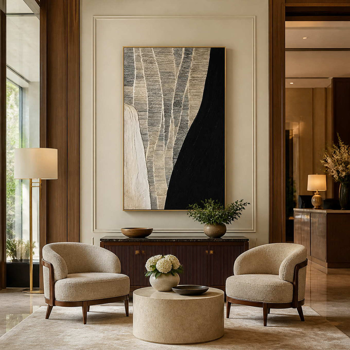 Gold framed black and cream artwork above a fluted cabinet between hotel lounge chairs.