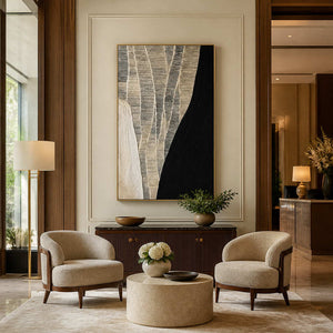 Gold framed black and cream artwork above a fluted cabinet between hotel lounge chairs.