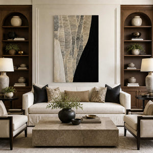 Frameless black and cream abstract artwork above a white sofa between wooden shelves.