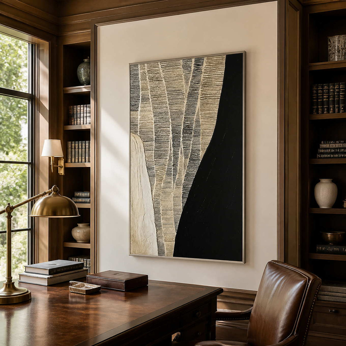 Silver framed woven abstract artwork above a wooden desk between library shelves.