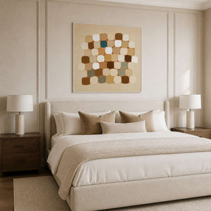 White framed warm square pattern above a cream upholstered bed and layered pillows.