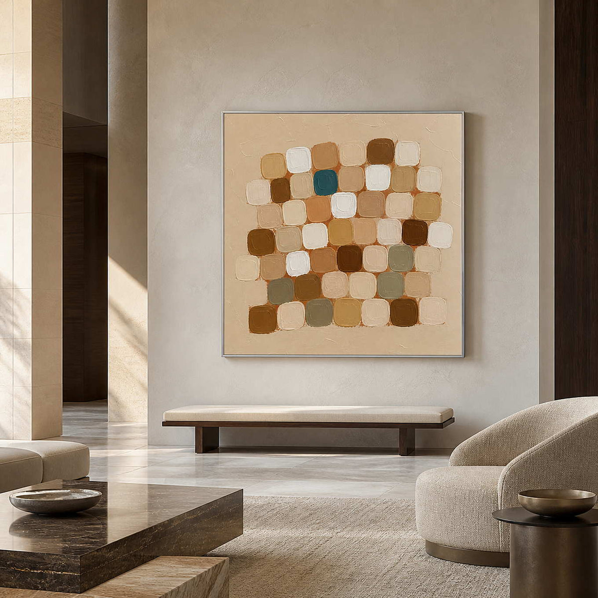 Silver framed square abstraction above a cushioned bench in a spacious neutral hall.
