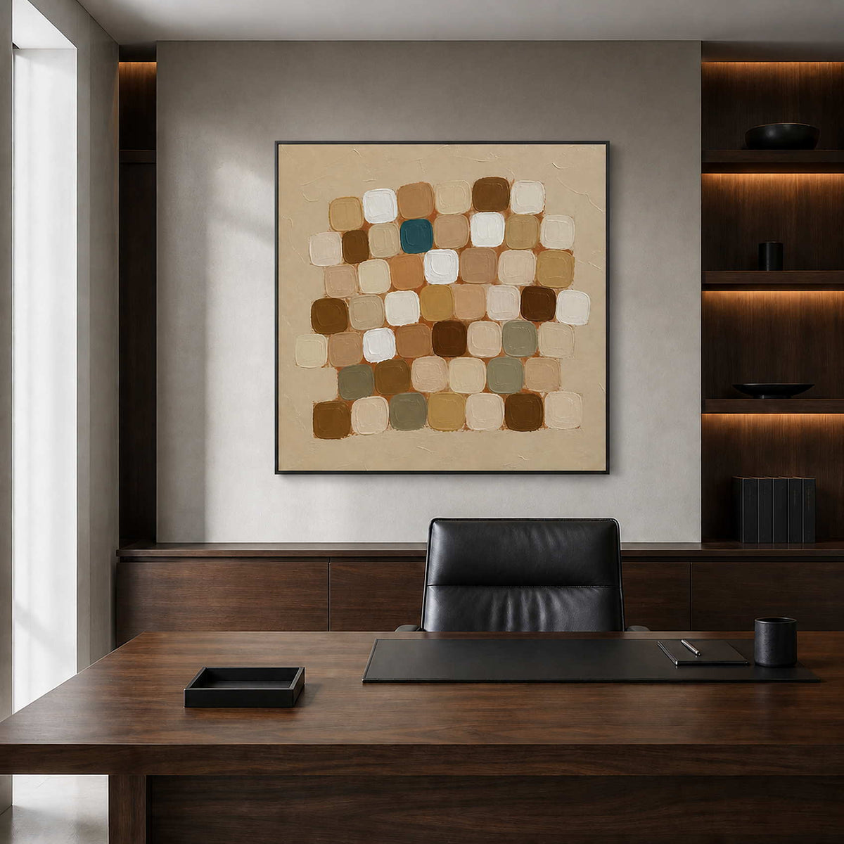 Black framed neutral squares behind a wooden office desk and black leather chair.