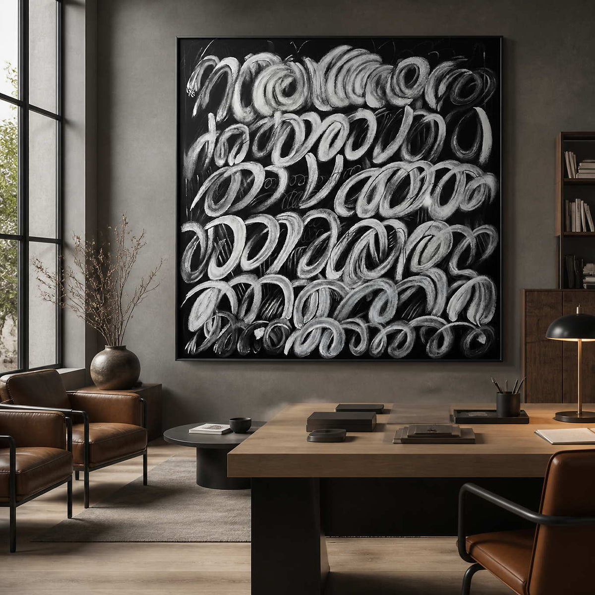 Black framed looping abstract painting displayed above a desk in a design studio.
