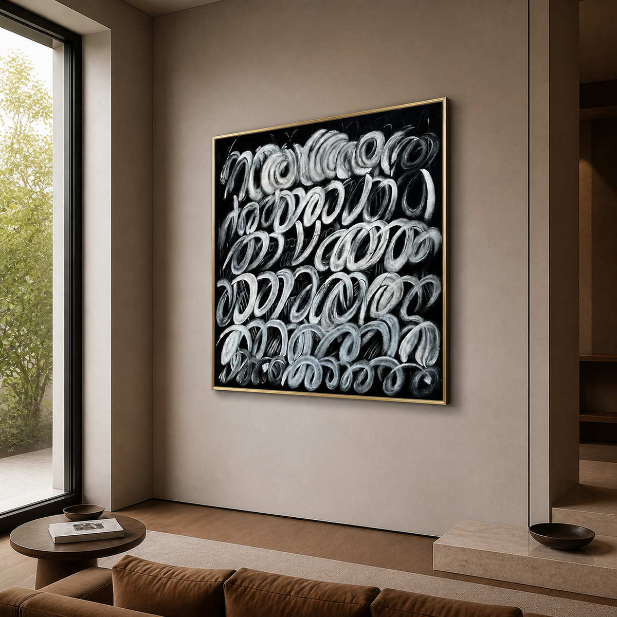 Gold framed black and white loop painting beside seating in a living room.