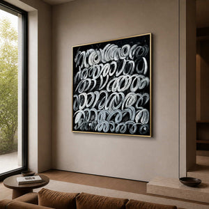 Gold framed black and white loop painting beside seating in a living room.