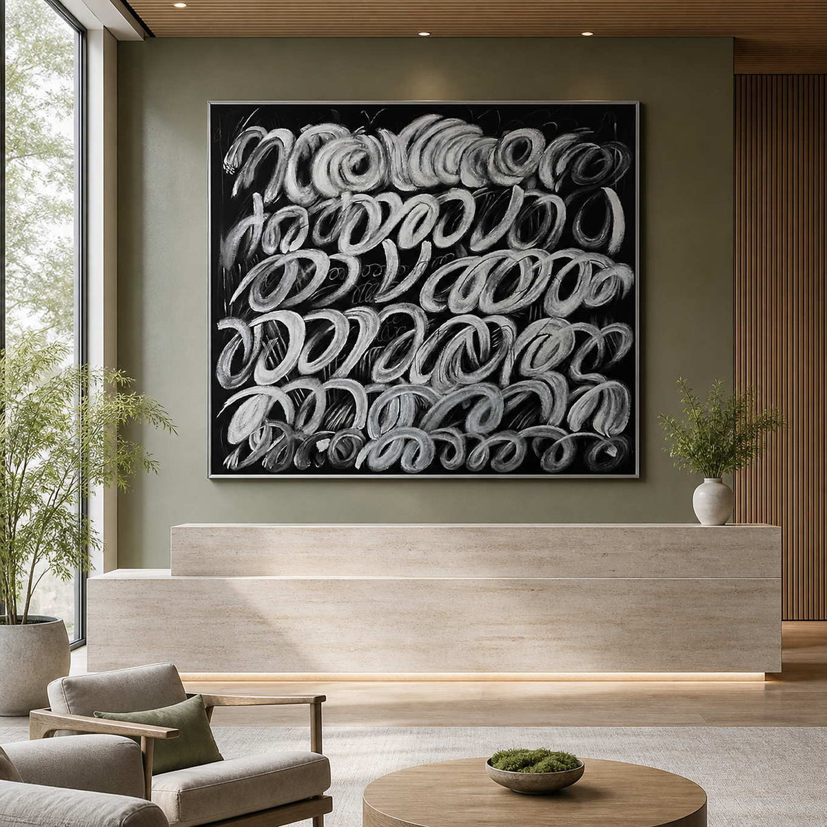 Silver framed monochrome abstract painting behind a pale stone wellness reception desk.